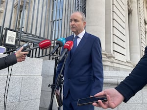 Micheal Martin standing outside, speaking into several microphones