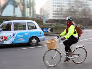 A cyclist wearing a high-visibility jacket on a roundabout