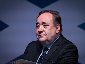 Head and shoulders photo of Alex Salmond in front of a Scottish flag