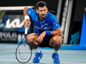 Novak Djokovic crouches down after hurting his left leg