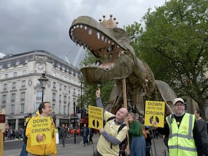 Republic protesters hold placards saying 'Down with the Crown' as they pose with Chuck the Rex - a 15ft T-rex puppet