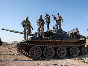 Syrian opposition fighters stand on a seized military armored vehicle on the outskirts of Hama,