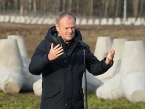 Donald Tusk standing in front of anti-tank barriers