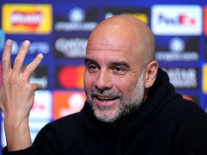 Pep Guardiola raises his hand at a press conference