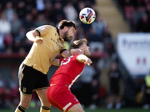 Two professional football players heading a football during a match