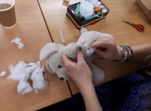 A volunteer repairs a soft toy