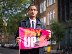 Daniel Kebede, General Secretary Elect of the NEU, holding a banner which reads 'pay up!'