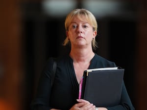 Shona Robison carrying a file and looking stern