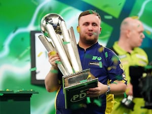 Luke Littler holds up the World Championship trophy