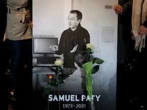 People hold a photo of history teacher Samuel Paty