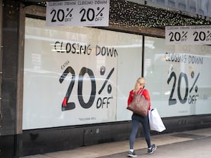 A shopper passing closing down sale signs in a shop