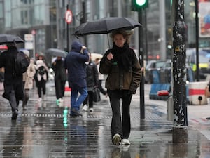 A person using an umbrella to shelter from the rain while walking in Shoreditch, London