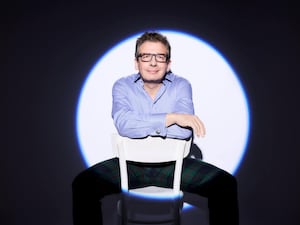 Benjamin Carey sitting on a chair in a spotlight