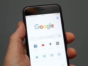 A person holds an iphone showing the app for Google chrome search engine