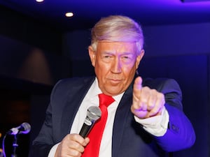 Man dressed as Donald Trump pointing at camera