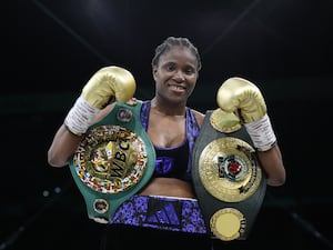 Caroline Dubois holds up her fists and belts after winning