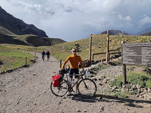 Man standing in a region of South America with his bike as he takes on a cycling and climbing challenge