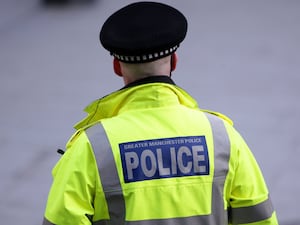 A police officer in a yellow coat with his back to the camera