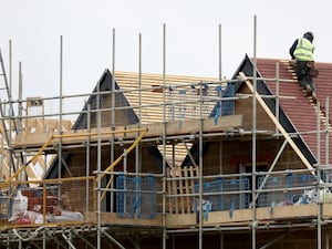 A worker on the roof of a house under construction