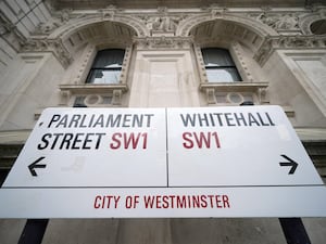 A street sign pointing to Parliament Street SW1 to the left and Whitehall SW1 to the right