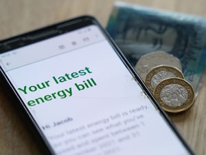 Energy bill displayed on a smart phone, with coins and banknotes beside it