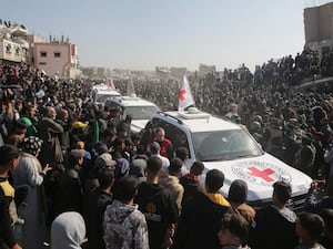 Red cross cars at handover site surrounded by crowd