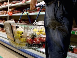 A person holding a shopping basket in a supermarket