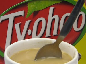 A mug of tea with a spoon in it, in front of a Typhoo box