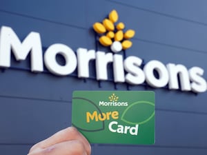 A Morrisons More Card held in front of a store sign