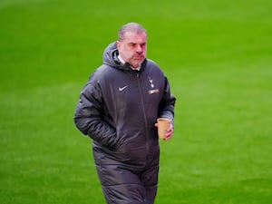 Ange Postecoglou carries a drink on the touchline