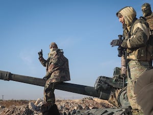 Syrian opposition fighters standing on a seized military armoured vehicle