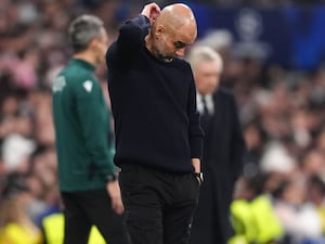 Pep Guardiola looks down as he scratches the back of his head