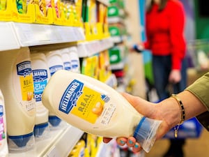 Shopper taking a Hellman's bottle off the shelf in a supermarket