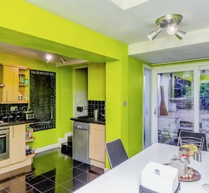 The kitchen of the property is painted in a bright yellow/green