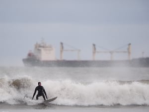 A surfer battles against the waves during strong winds