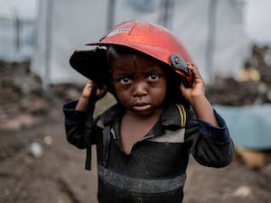 A child displaced by the fighting holds a damaged helmet