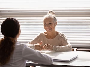 A smiling retired woman patient talking about health improvement with a therapist