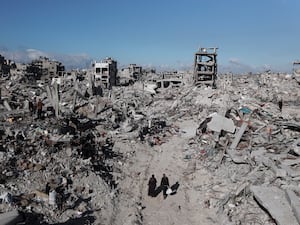 Palestinians walk through the destruction caused by the Israeli air and groun