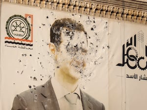 An image of Syrian President Bashar Assad, riddled with bullets, is seen on the facade of the provincial government office in the aftermath of the opposition’s takeover of Hama