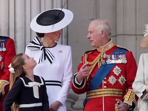 Kate turns to speak to the King on Palace balcony with the royal family