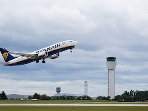 Ryanair plane taking off, with an airport tower in the background