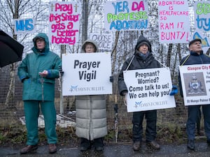 Anti-abortion protesters armed with placards, with pro-choice posters behind them