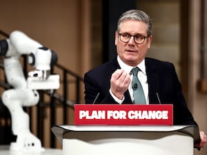 Prime Minister Sir Keir Starmer making a speech at a podium with a sign that reads Plan For Change