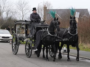 A horse-drawn hearse carrying The Vivienne's coffin arrives at the church for their funeral