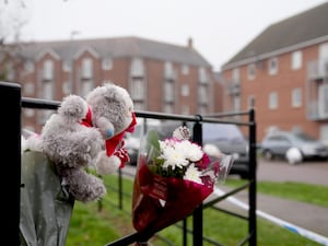 Floral tributes on a fence outside the scene of a double killing