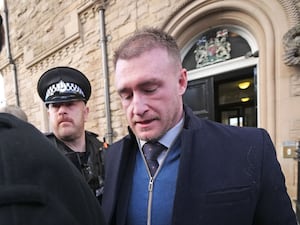 Stuart Hogg looks down while accompanied by police outside court