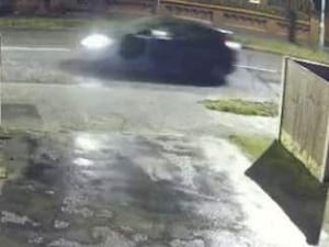 CCTV image of a black car driving at night