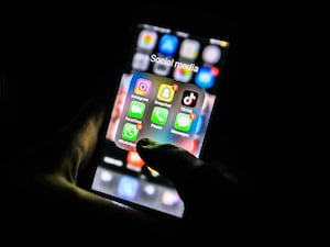 A young girl looks at social media apps, including TikTok, Instagram, Snapchat and WhatsApp, on a smartphone.