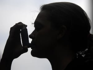 A silhouette of a woman using an inhaler