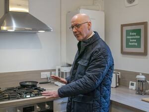 John Swinney in a kitchen checking out a gas hob